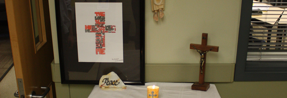 Alter with candle, crucific and framed photo of a cross made of words. 